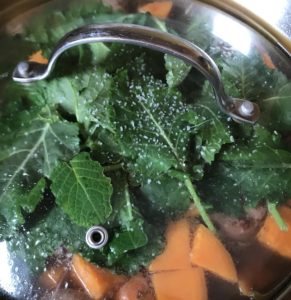 Kale and sausage added to sweet potatoes in broth