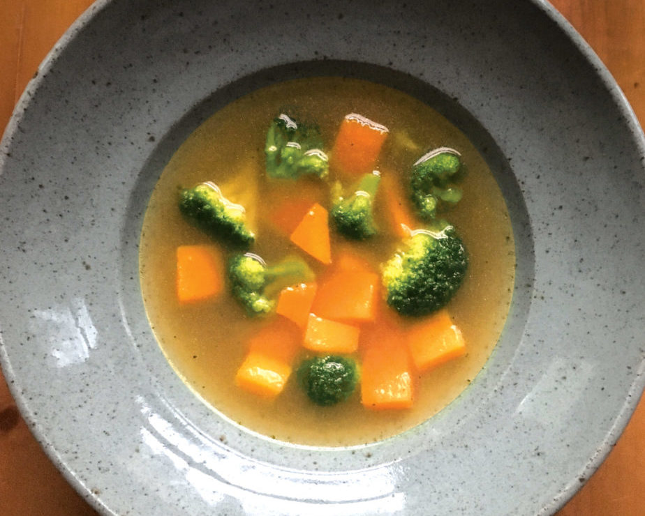 Bowl of chicken soup with broccoli and squash