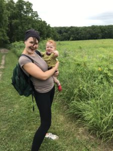 Maddy holding baby Lou on a hike through Midwestern prairie.
